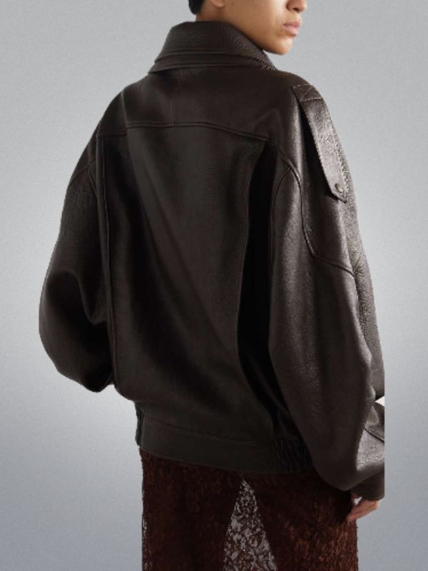 Person wearing a dark brown jacket on a plain background