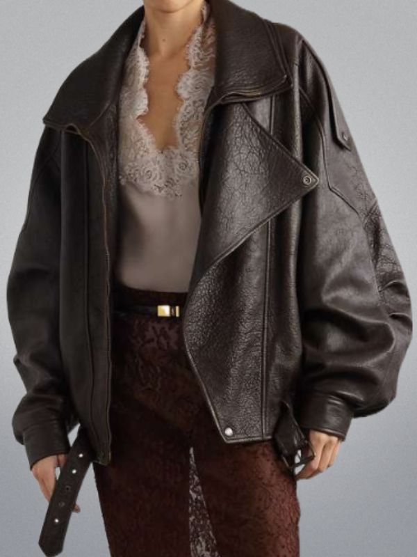 Person wearing a dark leather jacket over a lace top on a plain background