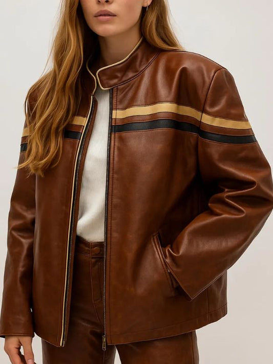 A person wearing a brown faux leather racer jacket with two horizontal stripes across the chest and arms – one tan and one black. The jacket has a high collar with a light trim and a zipper down the front. The person is also wearing a white ribbed top underneath.